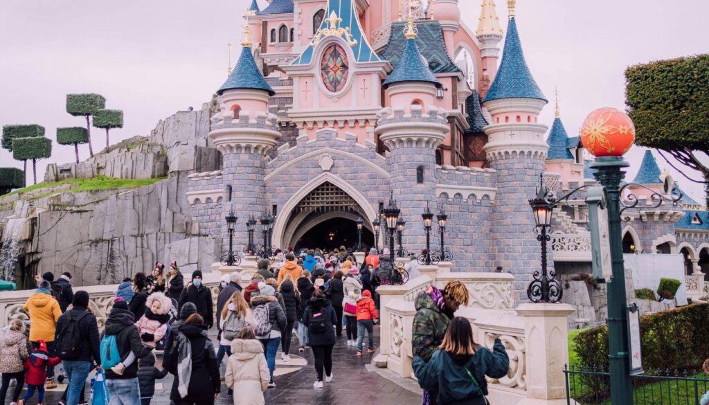 Colorful view of Tokyo Disneyland featuring the iconic Cinderella Castle surrounded by cheerful visitors, vibrant flowers, and magical decorations.